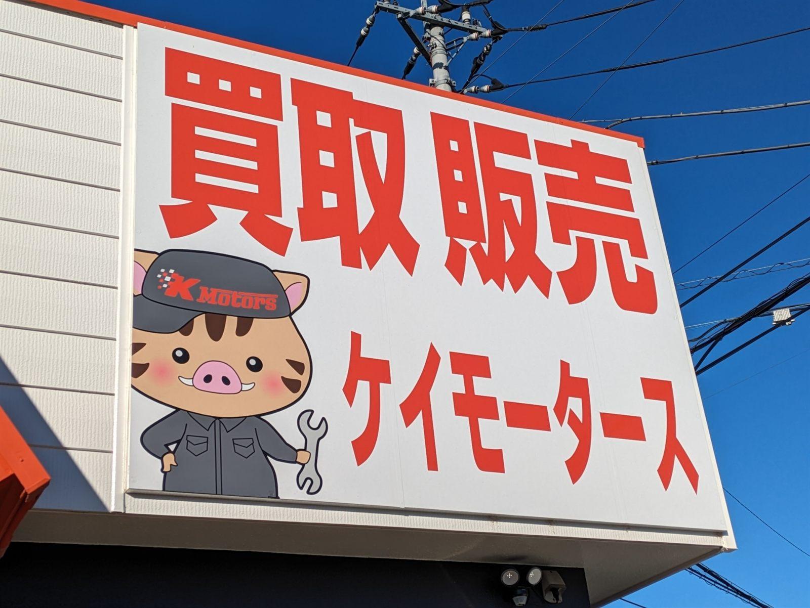 「買取 販売 ケイモータース」の看板とイノシシのキャラクター